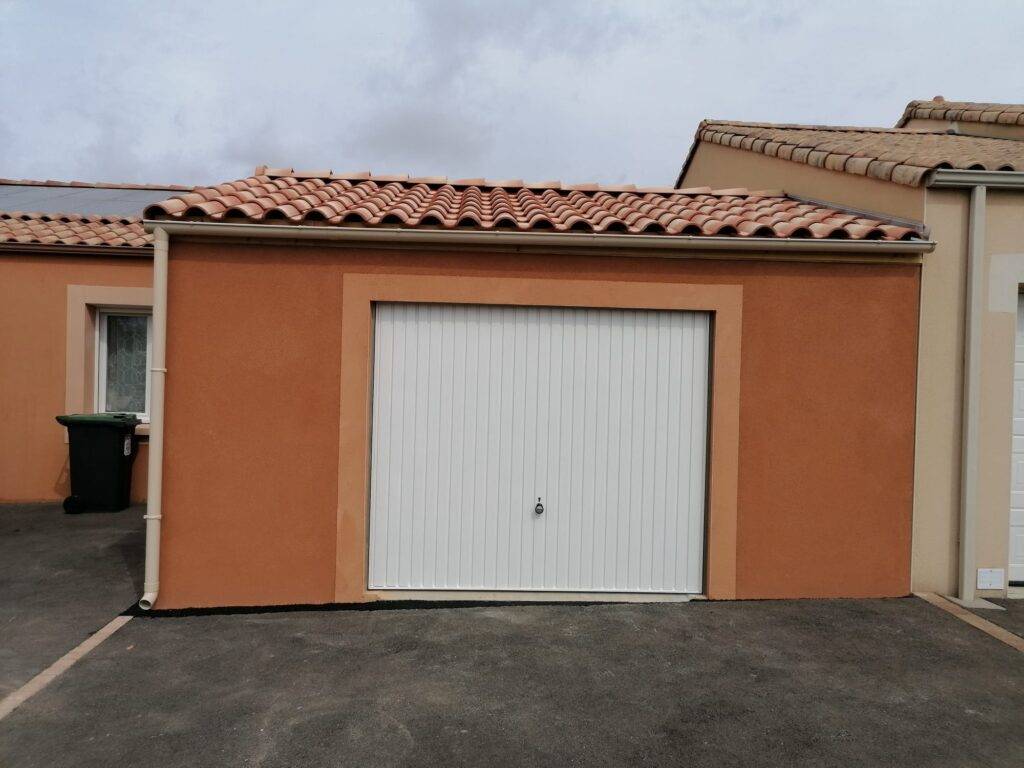 Garage béton préfabriqué finition enduit, double pente couverture tuiles, avec porte de garage basculante